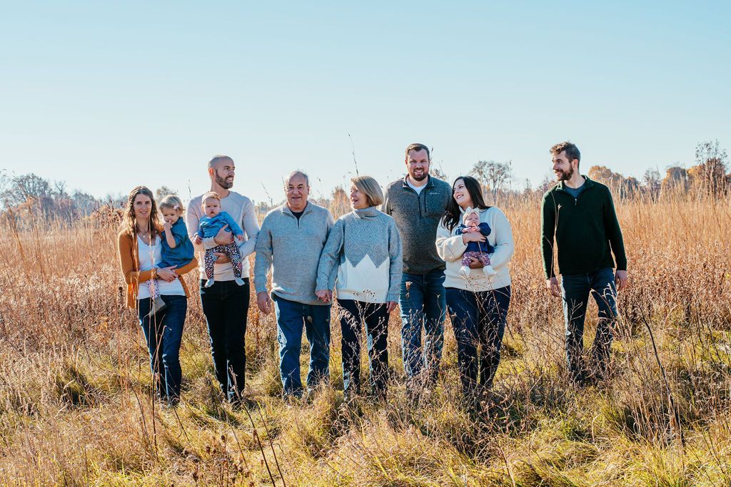 Six people standing in a tall grassy field under a clear blue sky
