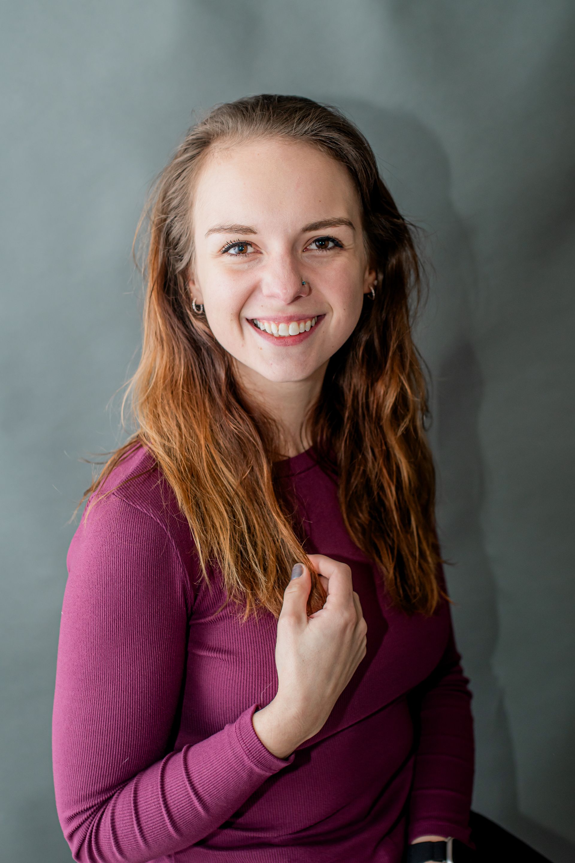 Smiling woman in a purple sweater against a gray background