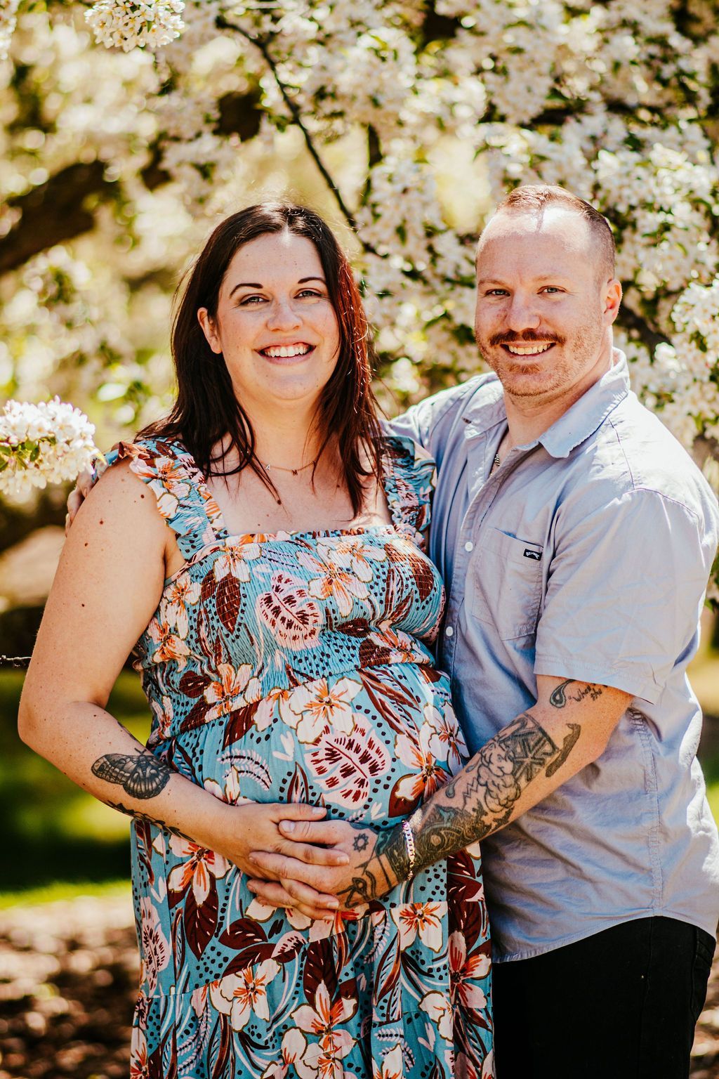 Couple smiling and embracing outdoors in front of blooming trees