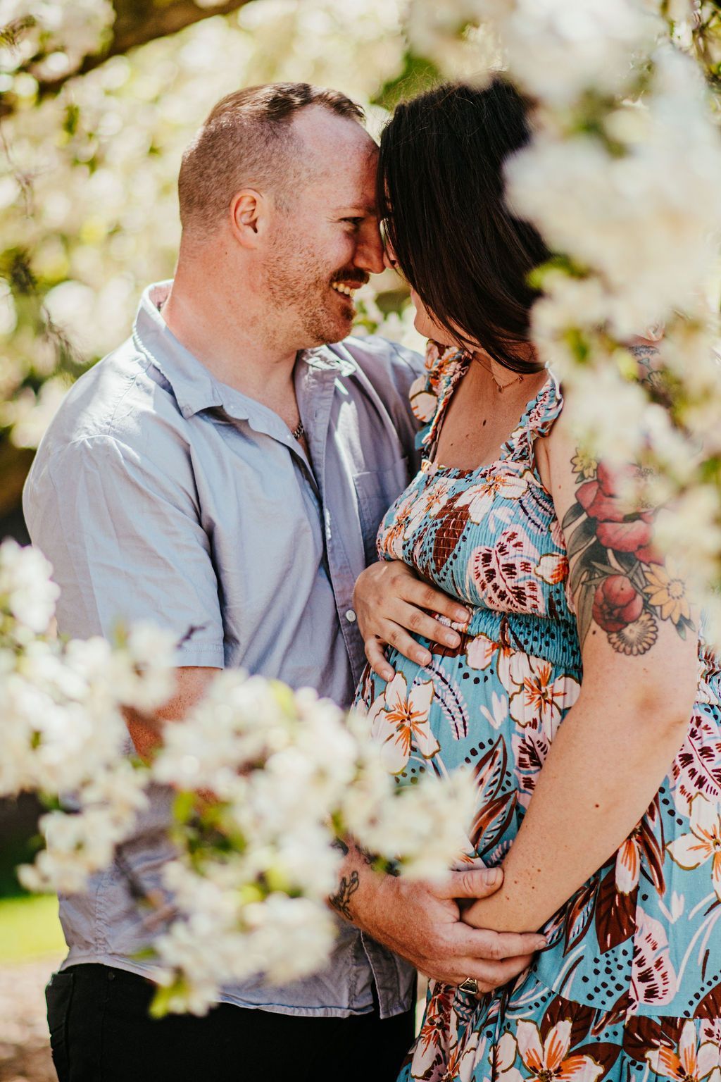 Couple holding hands and embracing in a flower-filled garden, smiling at each other.
