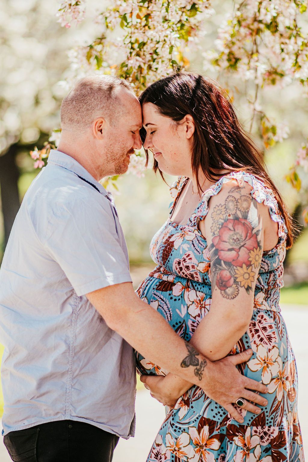 Couple holding hands and touching foreheads outdoors under blooming trees
