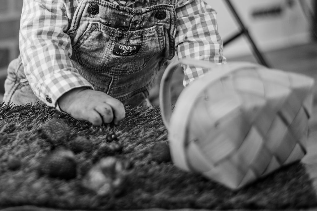 Child in overalls planting in soil beside a tipped basket