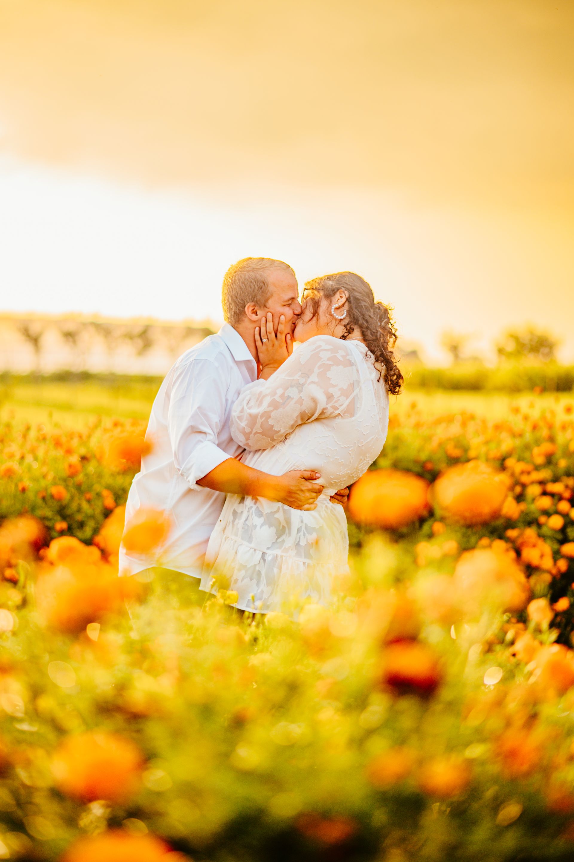 Couple embracing in a sunlit pumpkin field with warm golden tones