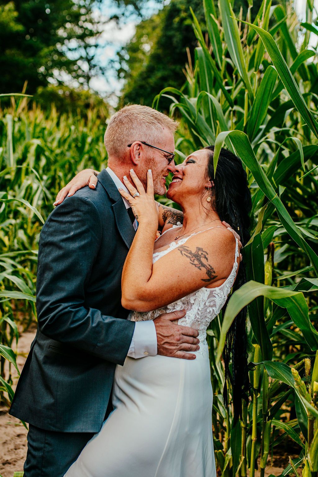 A couple kissing in a cornfield, with the man in a dark suit and the woman in a white dress.