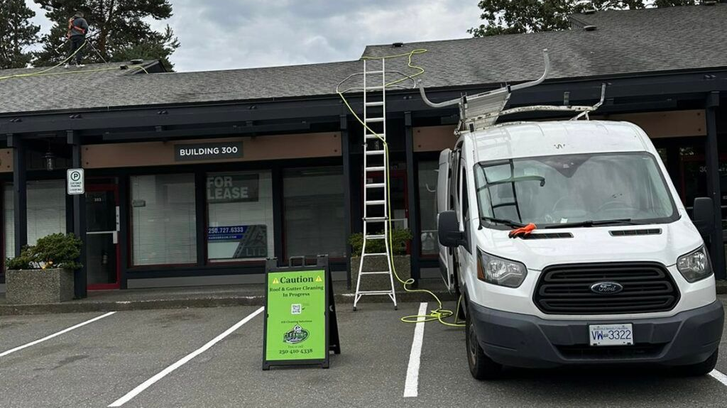 Small storefront with a white van parked outside and a green sign in front under an overcast sky.