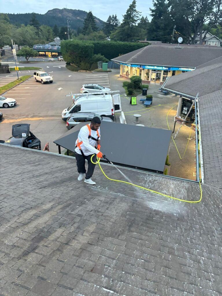 HB cleaning employee soft washing a roof