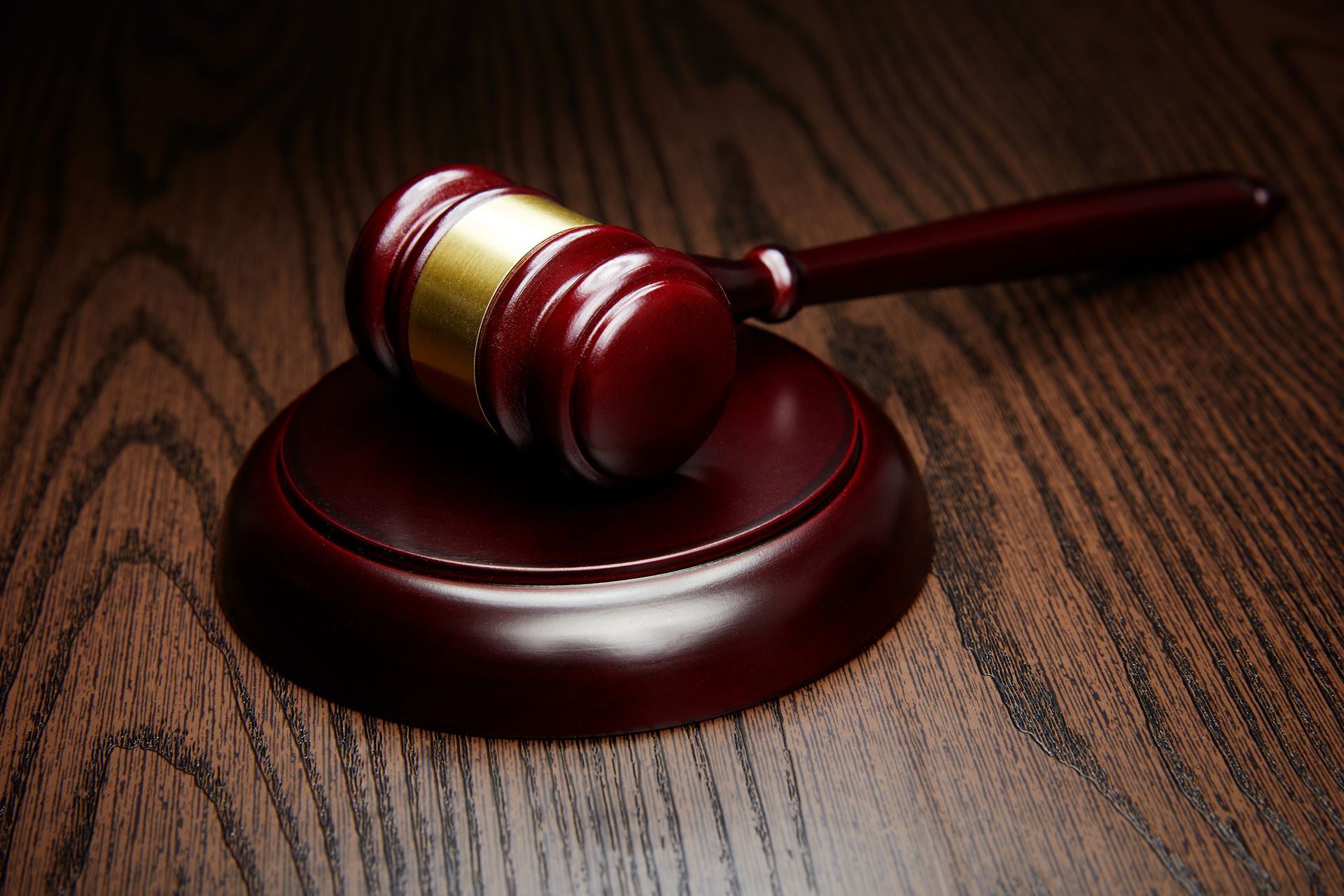 A wooden judge 's gavel is sitting on a wooden table.