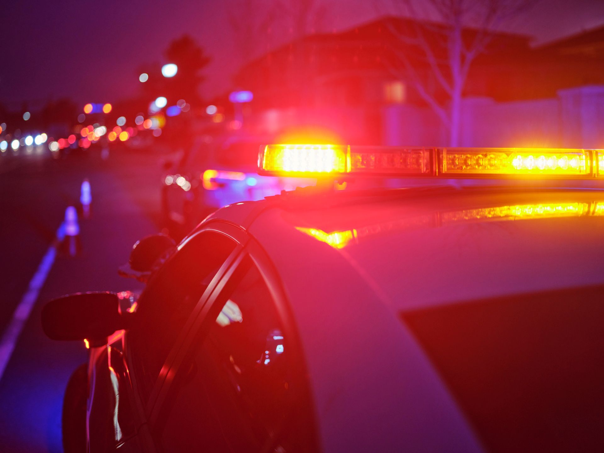 A police car is parked on the side of the road at night with its lights on.