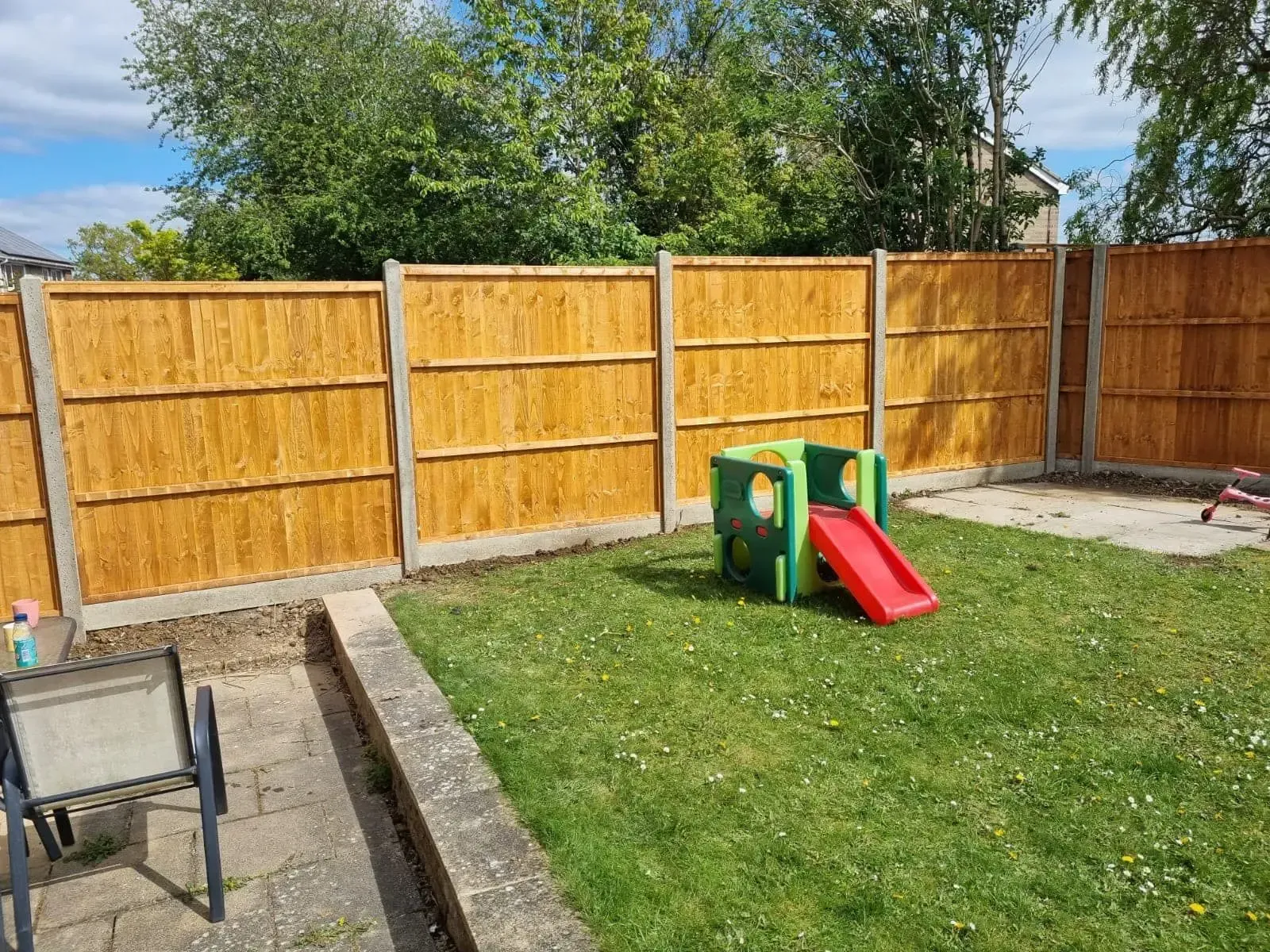 Newly installed pressure-treated closeboard fence panels dropped into slotted concrete posts and concrete gravel boards