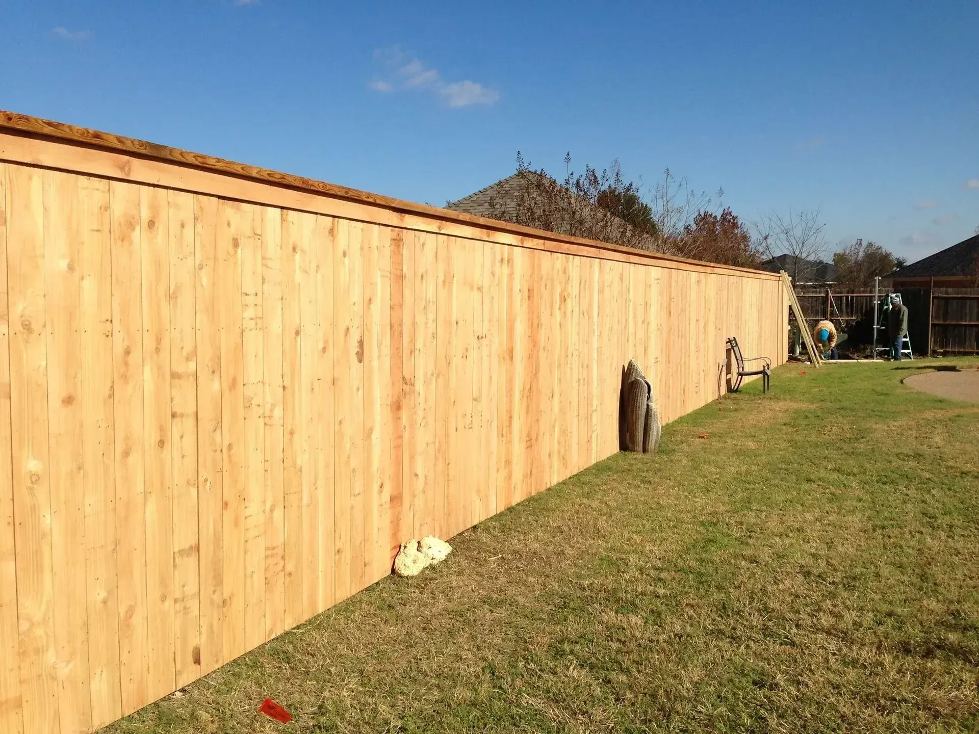 Contractors finishing a long run of vertical timber privacy fencing on a residential perimeter in Edinburgh