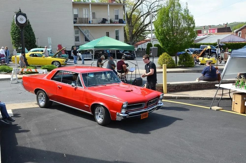 Red classic car parked at an outdoor car show with spectators and tents in the background | Hermansaders Garage & Auto Sales
