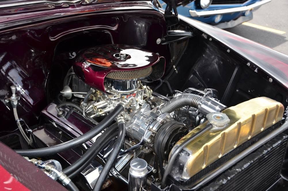 Custom car engine bay with polished chrome engine and gold radiator under a maroon hood | Hermansaders Garage & Auto Sales