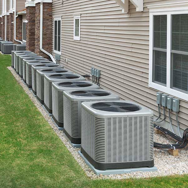 Multiple Air Conditioning units in a row behind apartments