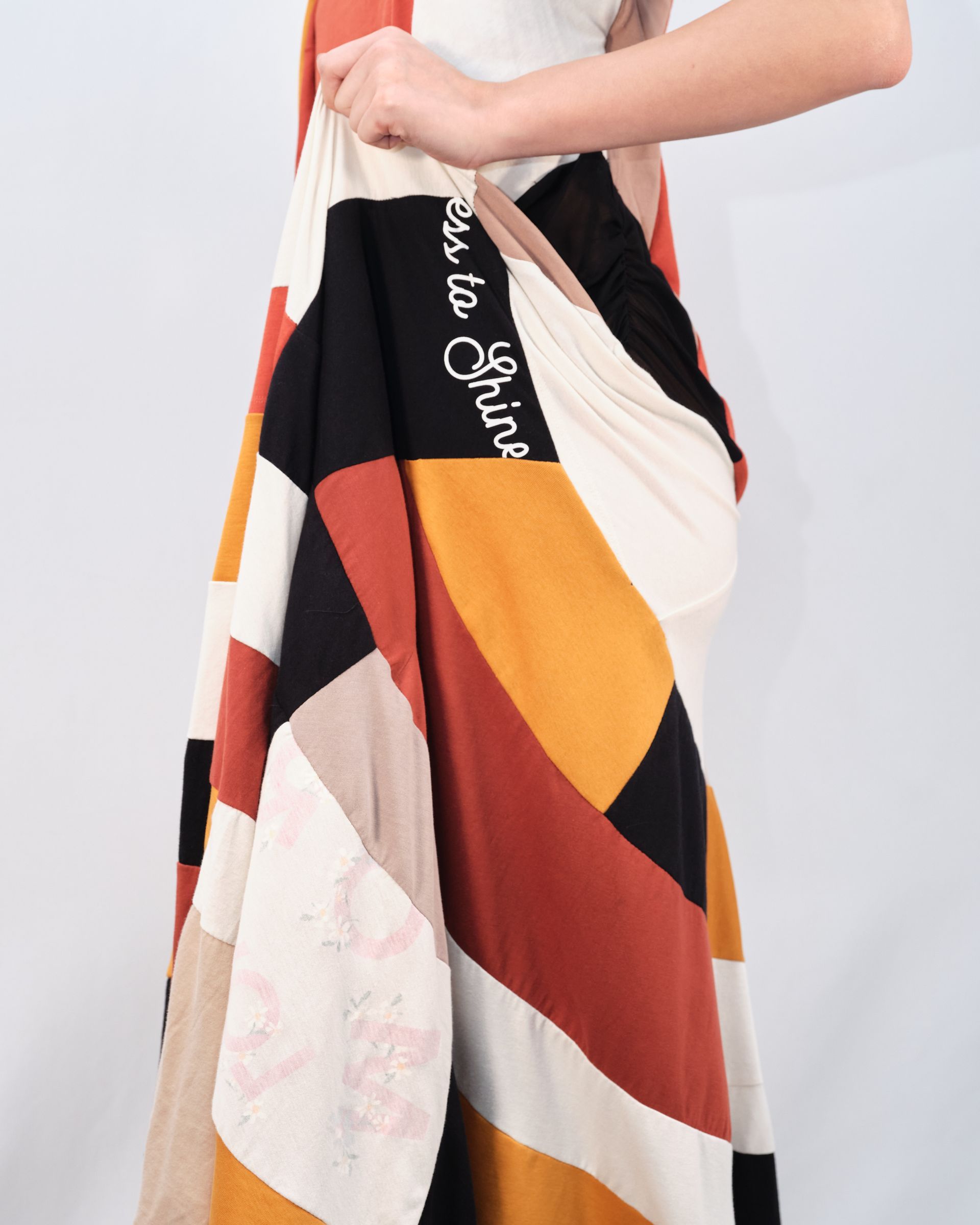 A woman is holding a colorful blanket that says tea to girls