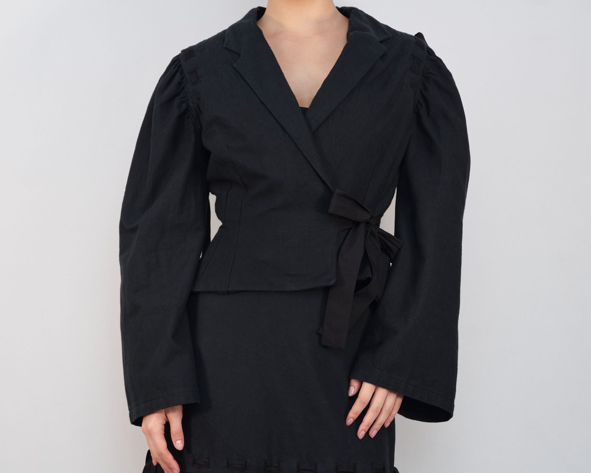 A woman is wearing a black jacket and a black skirt