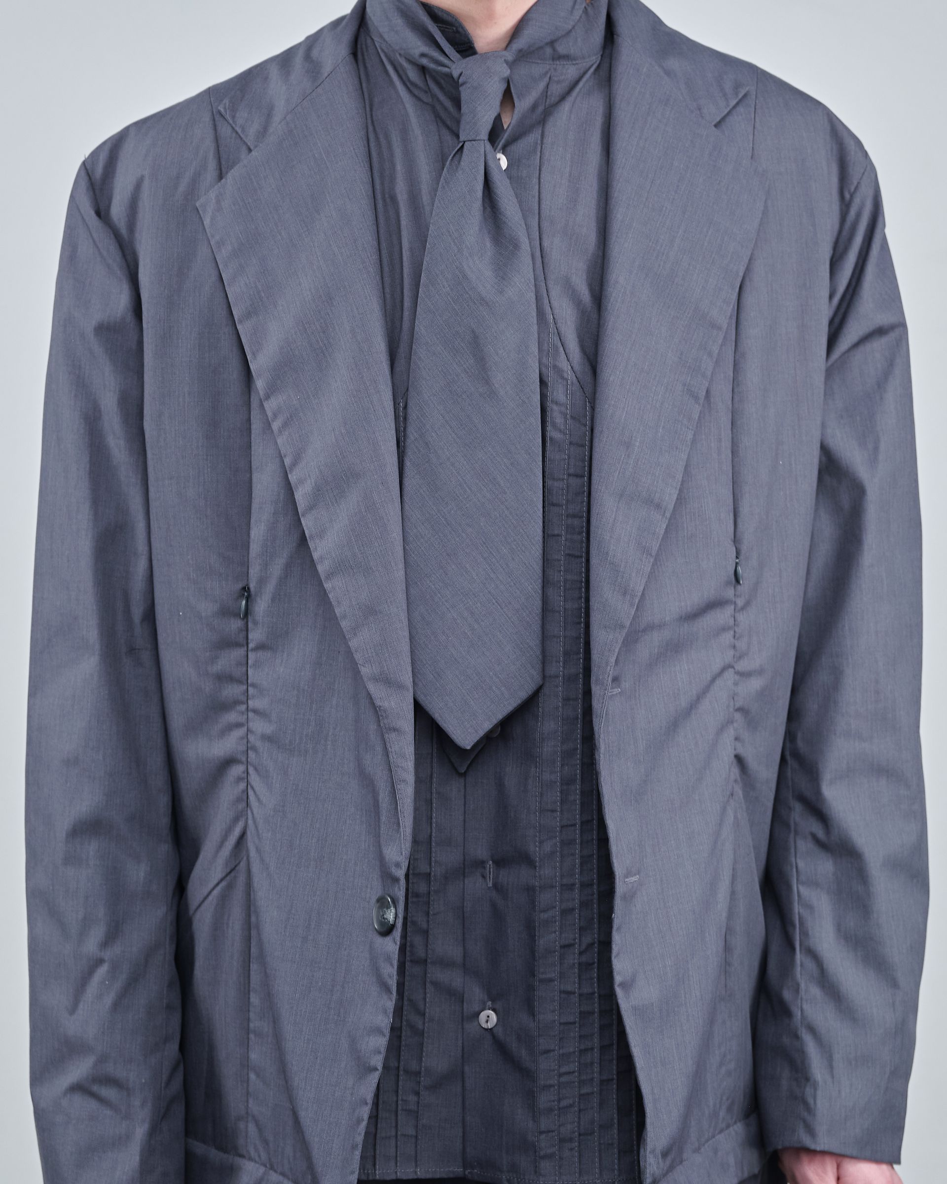A man is wearing a grey jacket and tie