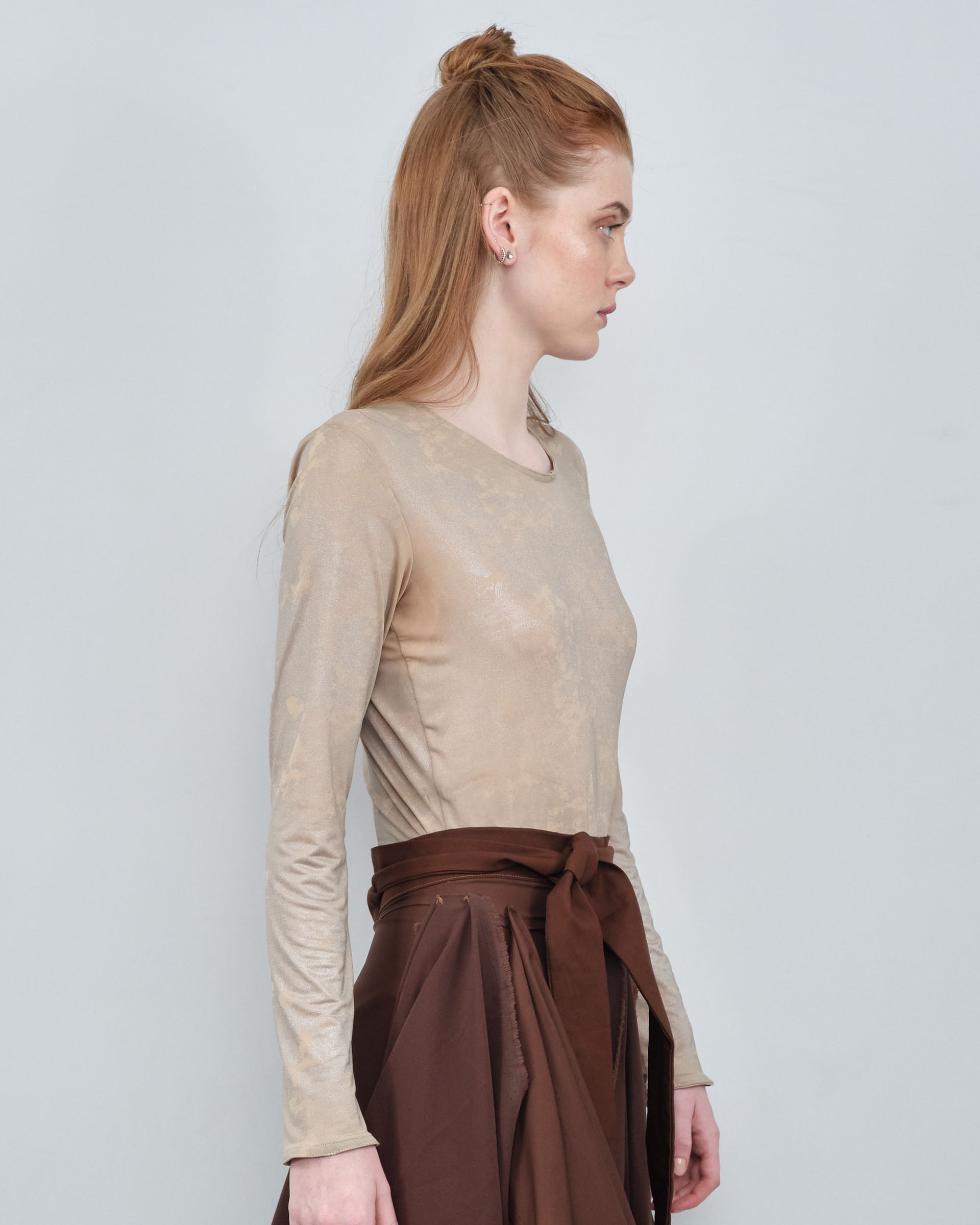 A woman is wearing a long sleeve top and a brown skirt.
