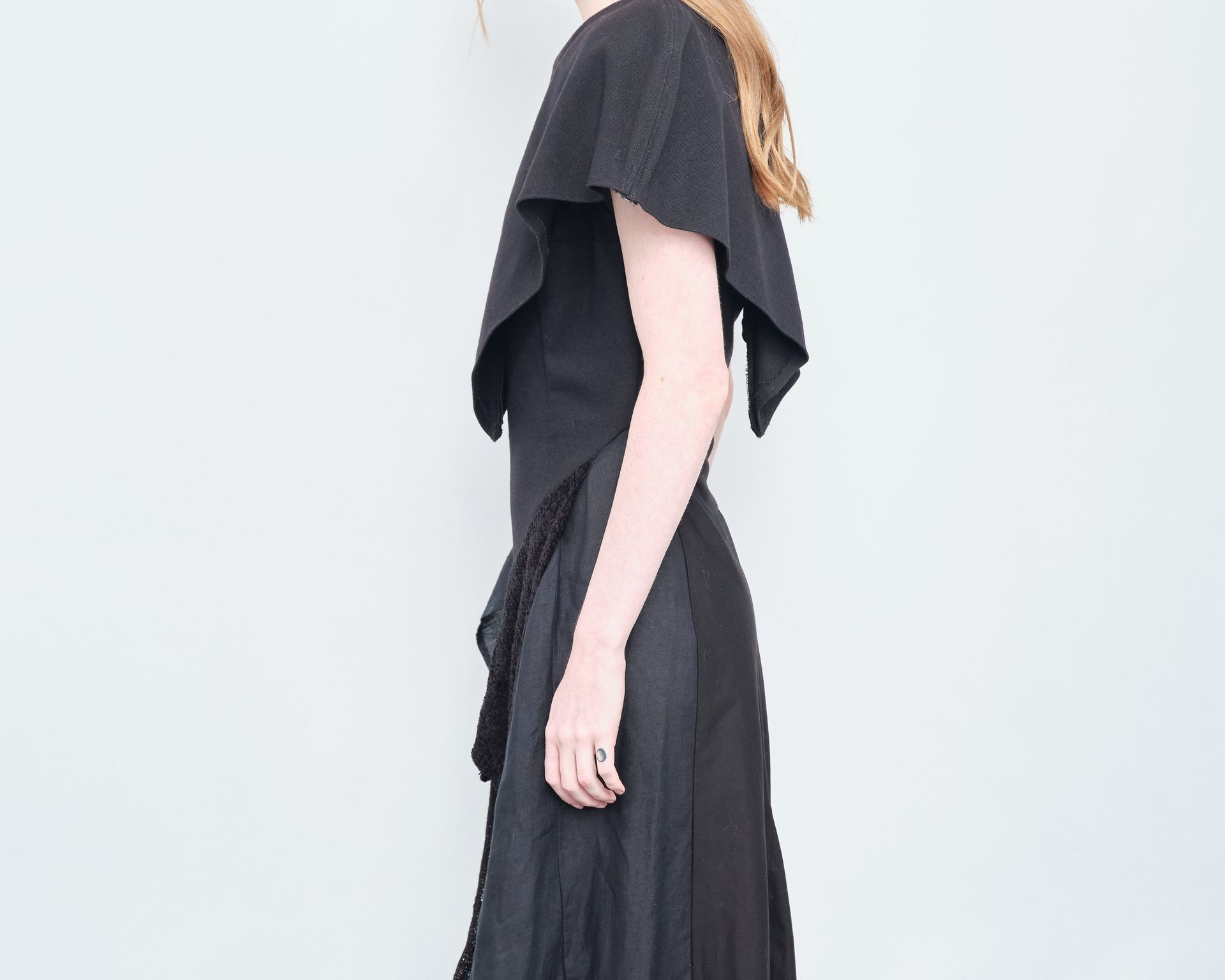 A woman in a black dress is standing in front of a white wall