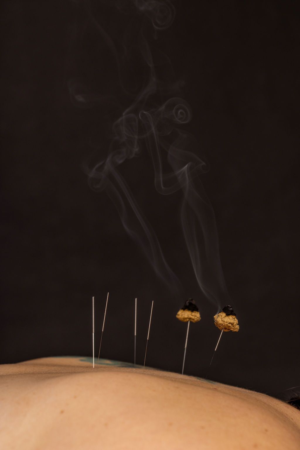 A dark desert scene with a sandy dune, thin poles, and smoke or light trails in the sky.