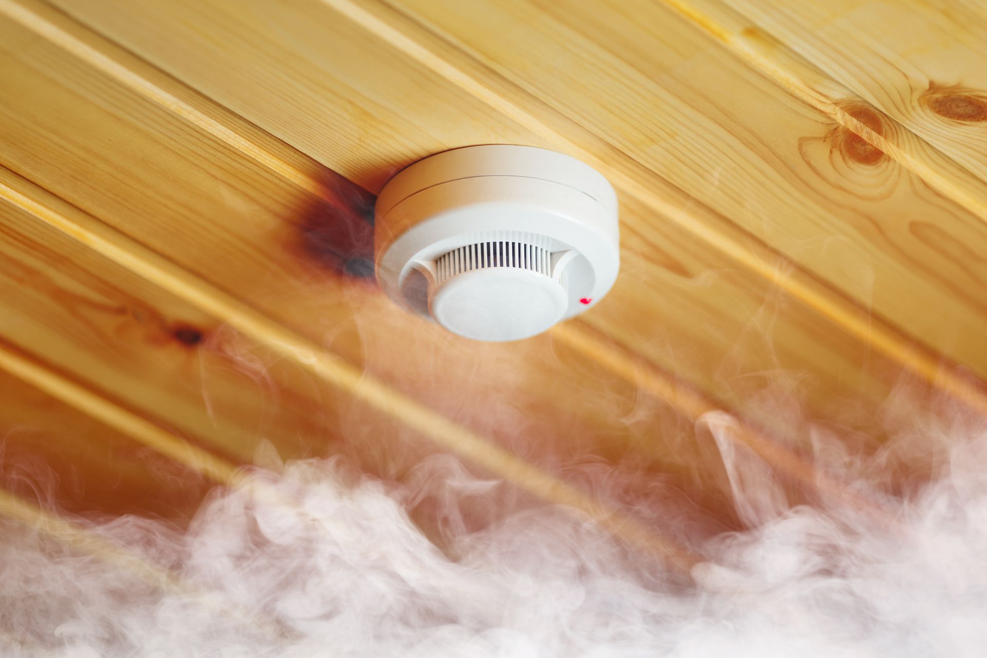 A Smoke Detector on a Wooden Ceiling With Smoke Coming Out of It — Alert Smoke Alarm Compliance in Hervey Bay, QLD
