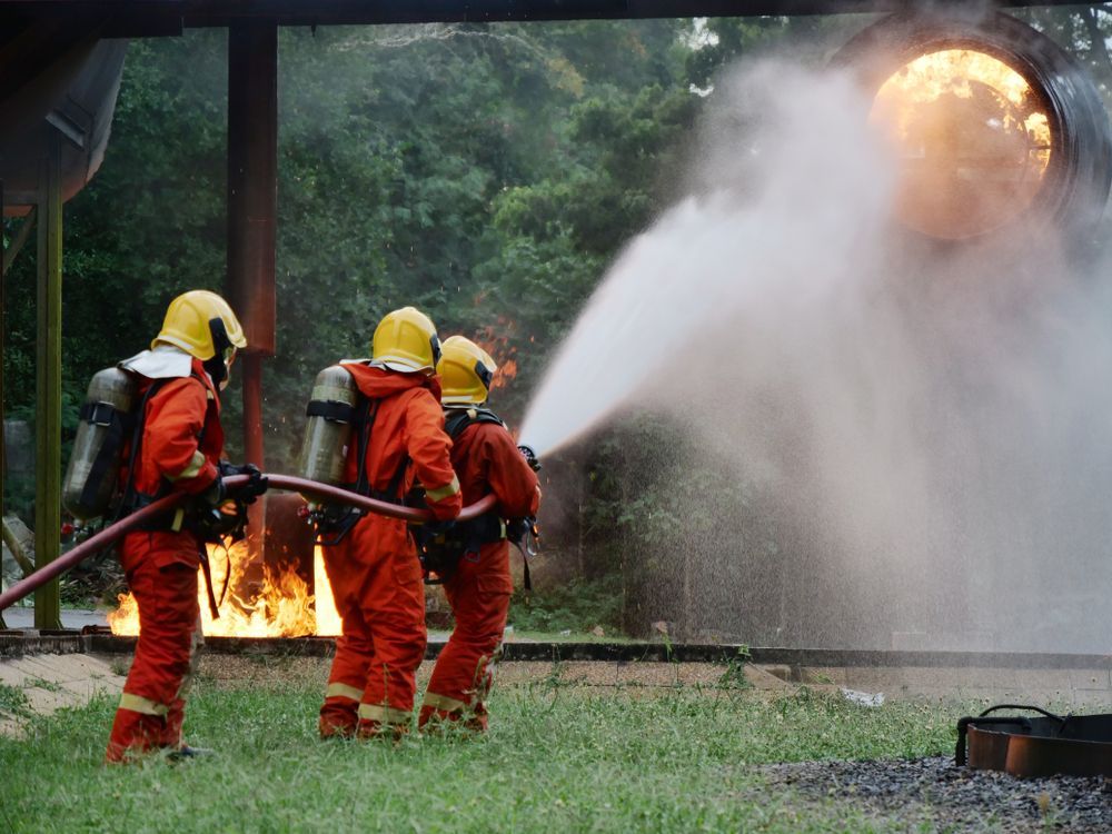 Firefighters in Orange Gear Spray Water at a Blaze and Smoke — Fitzroy Fire and Safety in Rockhampton, QLD
