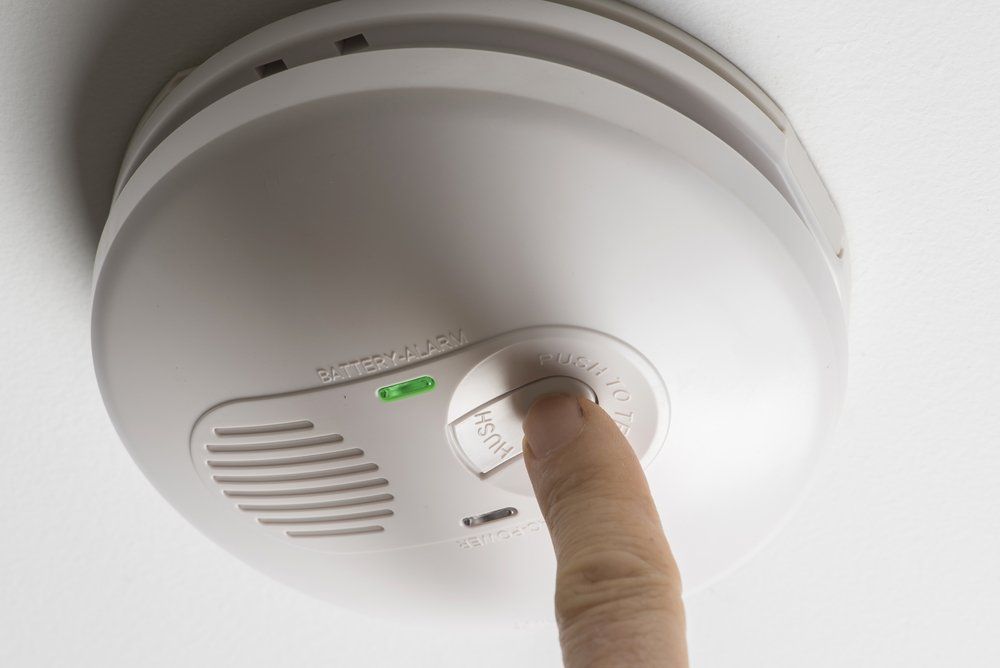Finger pressing test button on white smoke detector — Fitzroy Fire and Safety in Kawana, QLD