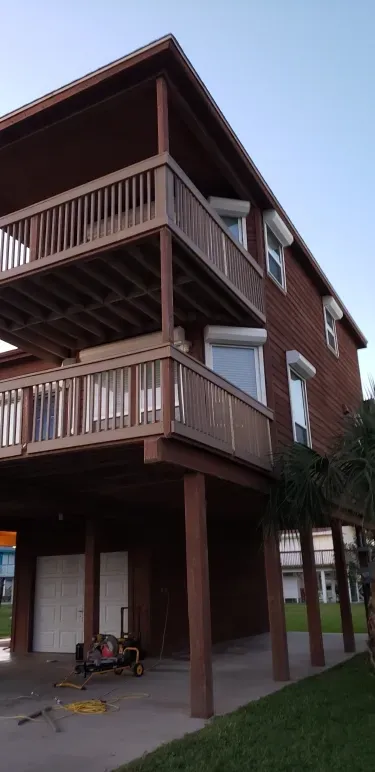 Three-story brick building with wooden balconies and a covered ground-floor patio