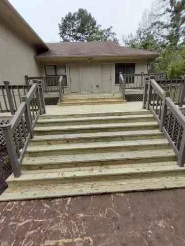 Outdoor staircase with wide wooden steps and metal railings leading to a building entrance