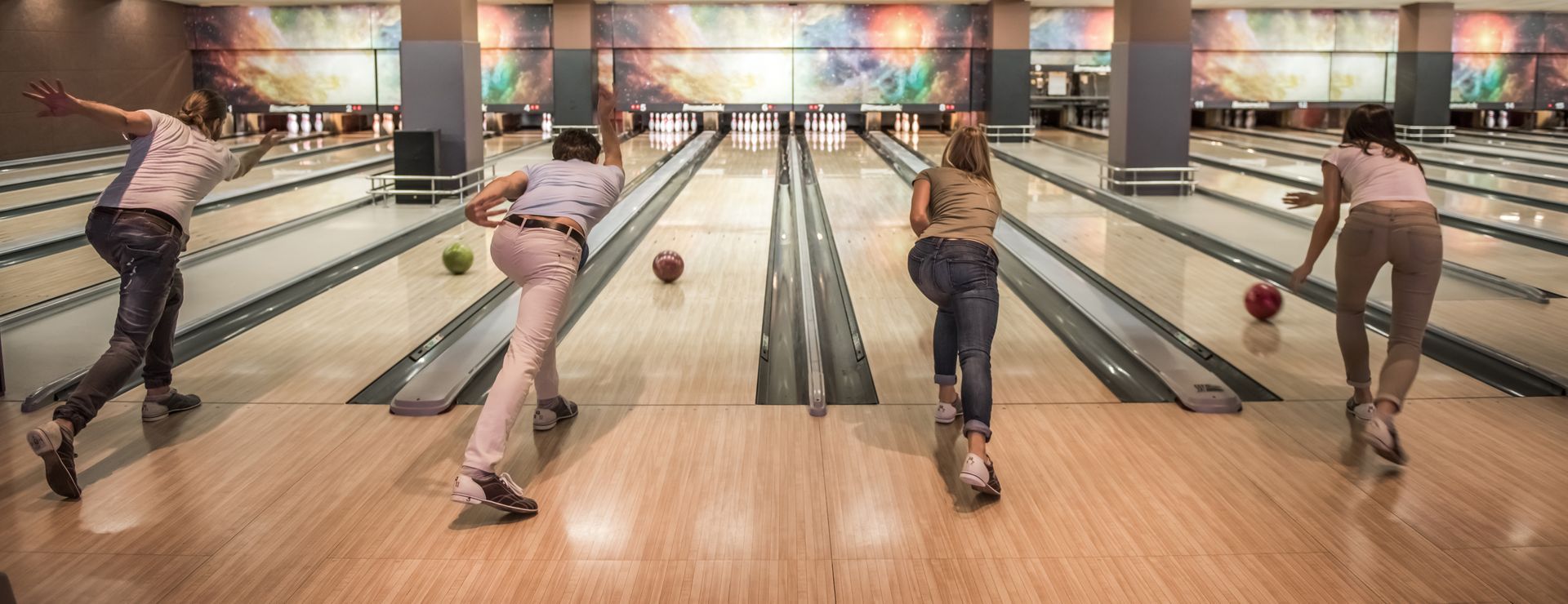 Two people bowling in a modern bowling alley with colorful lanes