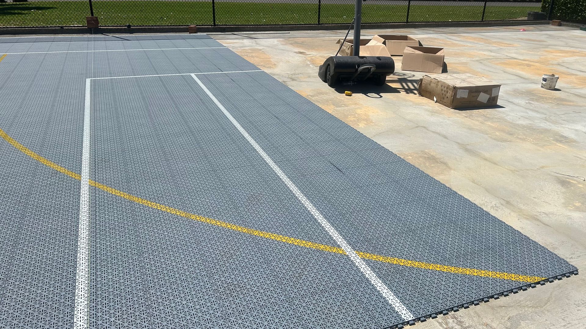 Blue-gray gravel path with white edging and a yellow line, beside construction materials on concrete.