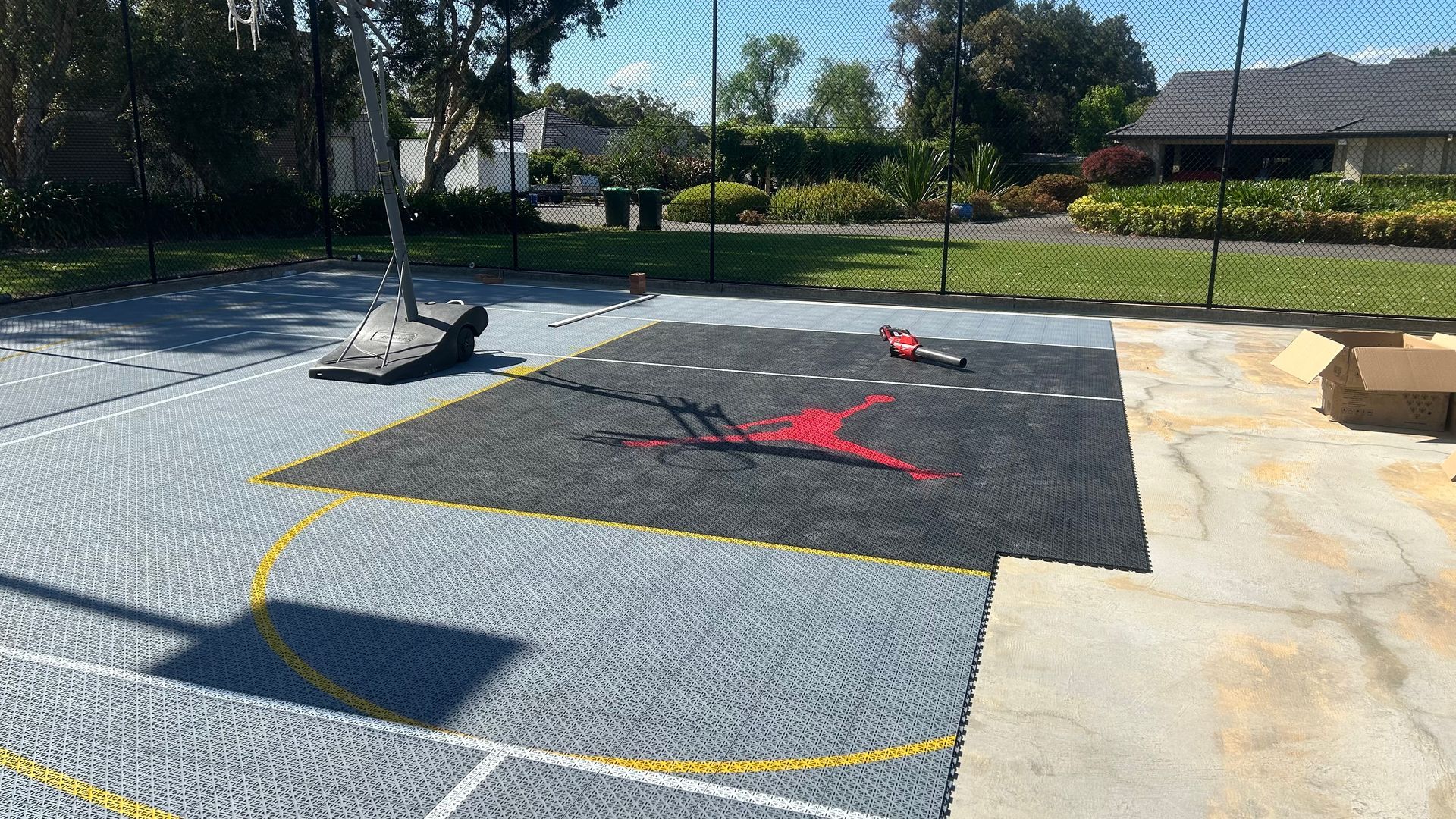 Outdoor playground with black safety mats, colorful chalk markings, and trees in the background