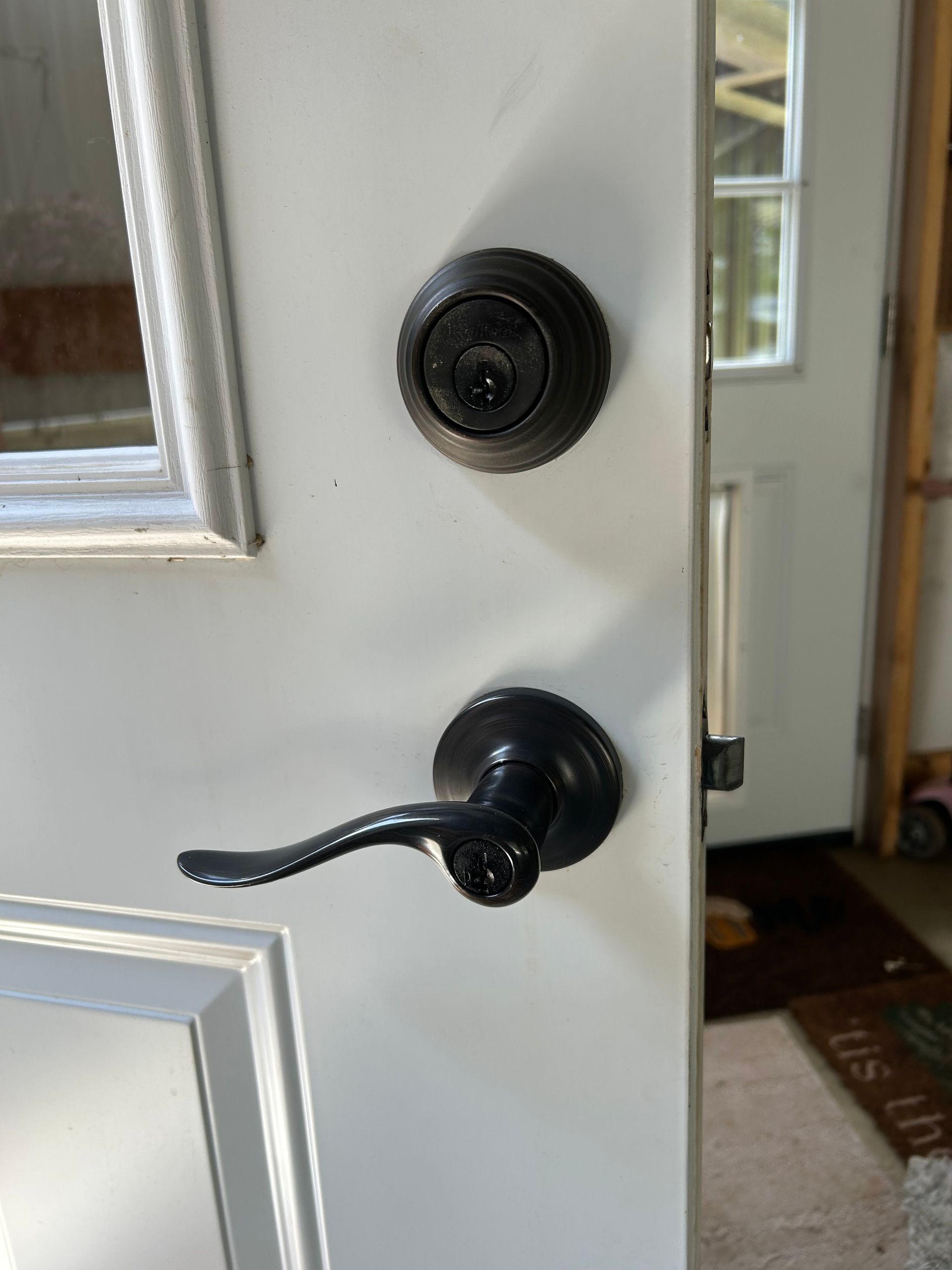 White door with a black deadbolt and lever handle.