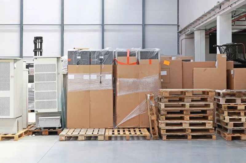 A warehouse filled with lots of cardboard boxes and wooden pallets.