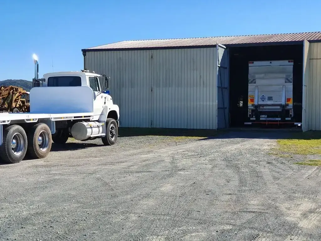 A Truck With A Flat Bed Is Parked In Front Of A Building — Geisler Truck & Trailer Wheel Alignments In Pleystowe, QLD