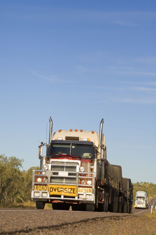 A Large Semi Truck Is Driving Down A Dirt Road — Geisler Truck & Trailer Wheel Alignments In Mackay, QLD