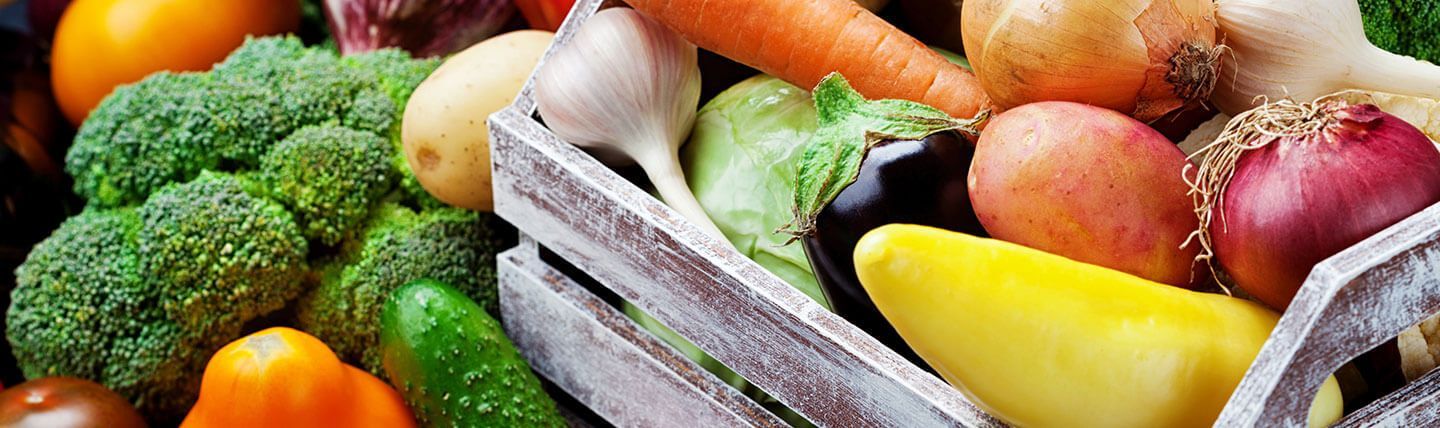 a wooden box filled with a variety of vegetables .