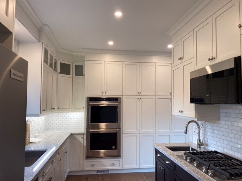 White kitchen with cabinets, stainless steel appliances, and a dark island.