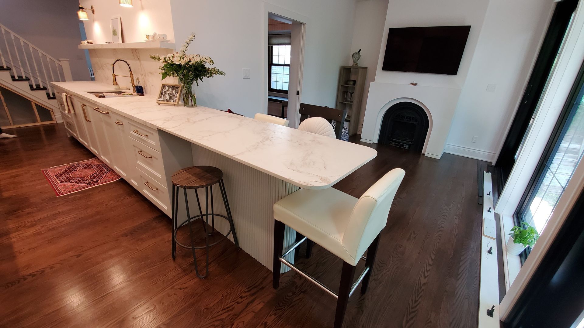 Kitchen with white cabinets, marble countertop, wooden floor, and a fireplace.