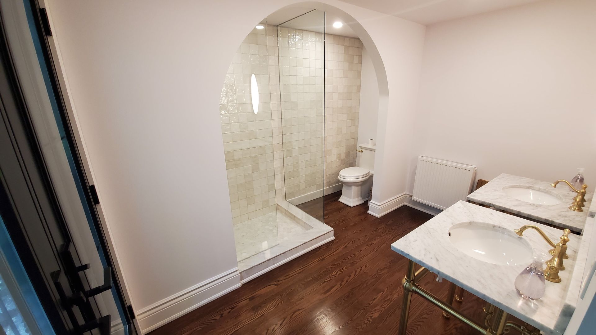 Bathroom with a shower in an arched alcove and two sinks.