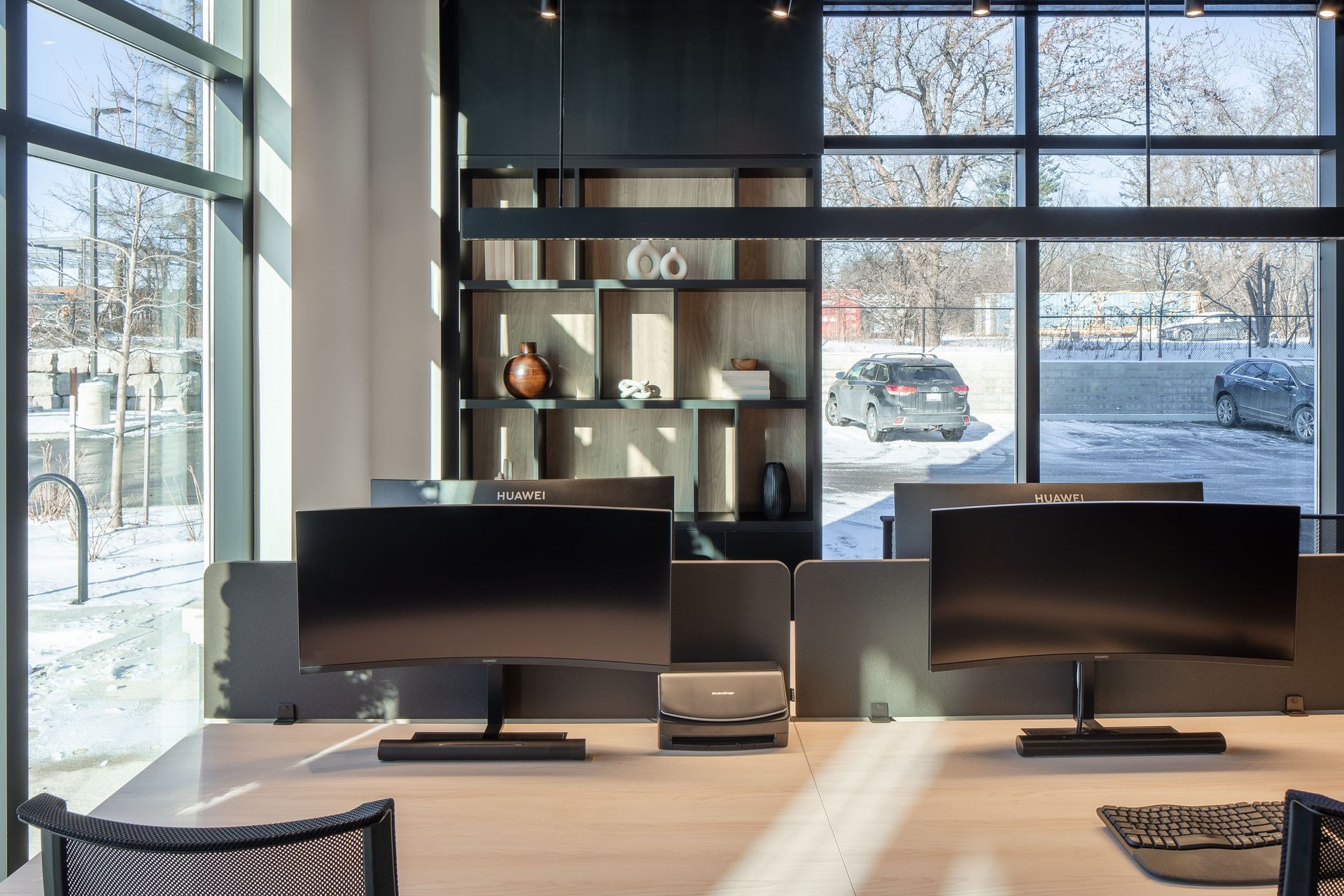 Modern office space with desks and computer monitors, large windows overlooking a snowy landscape.