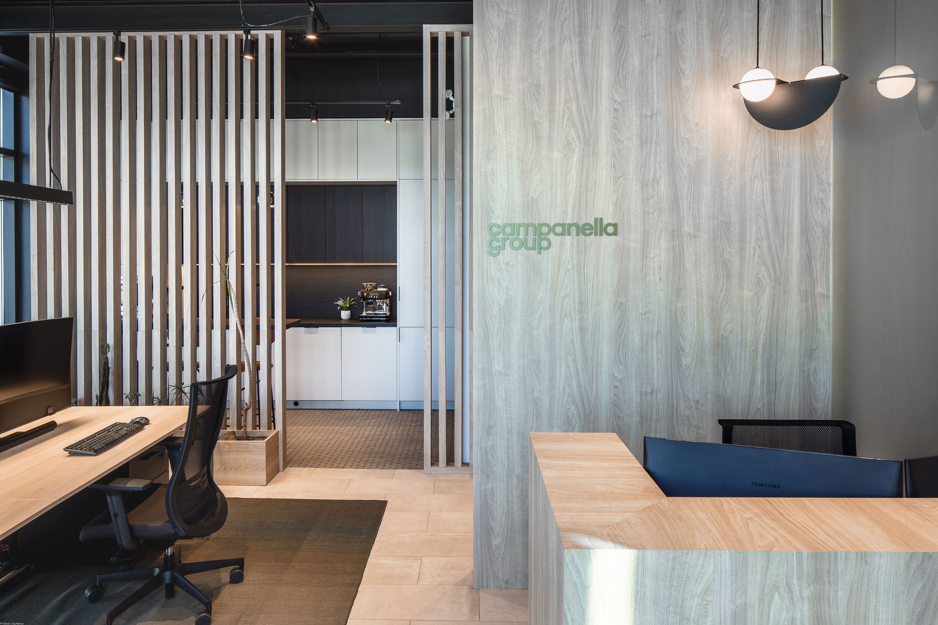 Modern office reception area with wood paneling, slatted divider, and desk.