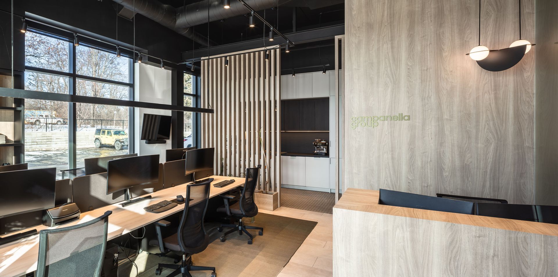 Modern office interior with workstations, large windows, and a reception area.