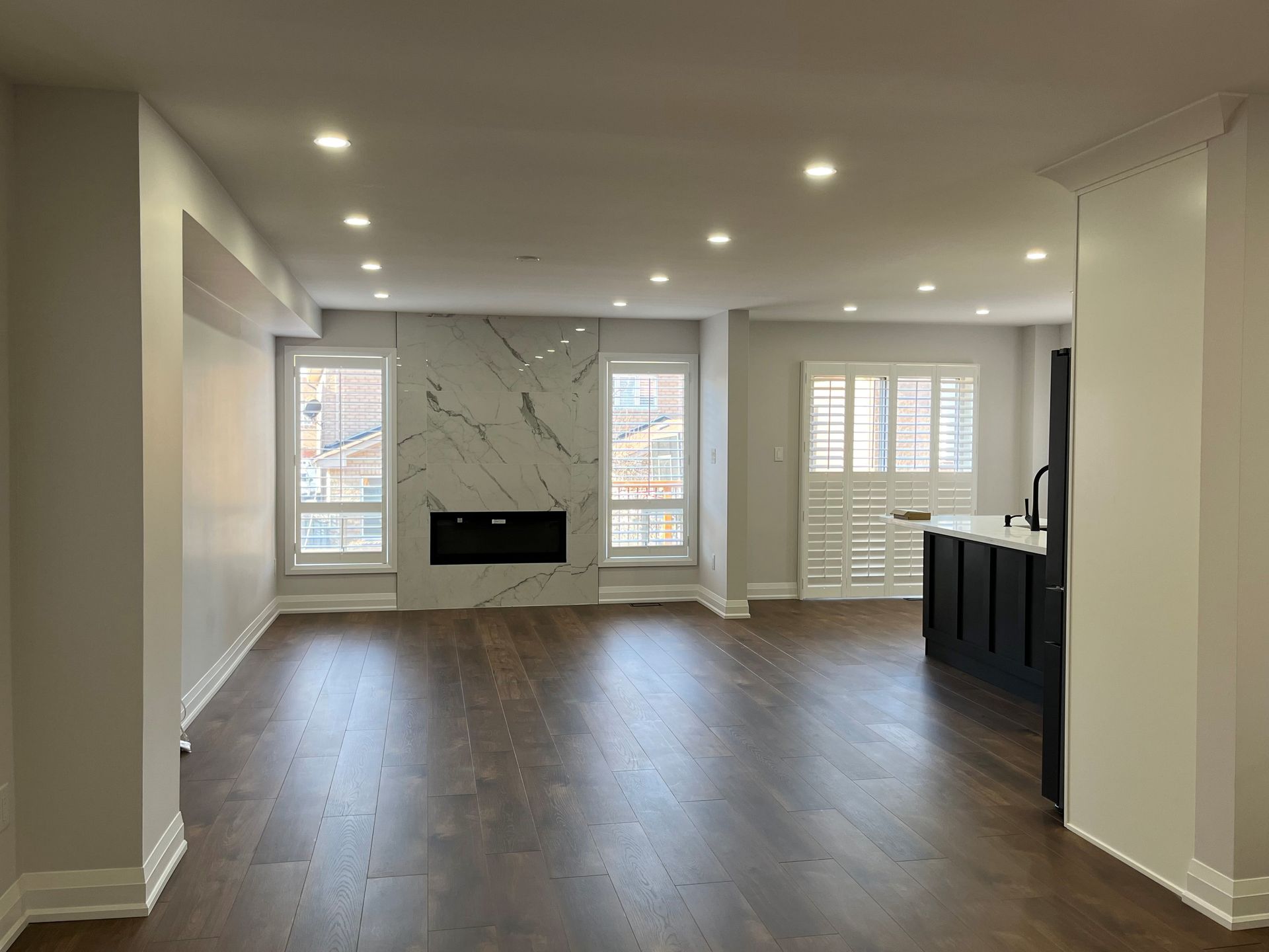 Empty, modern living room with fireplace and dark wood flooring.