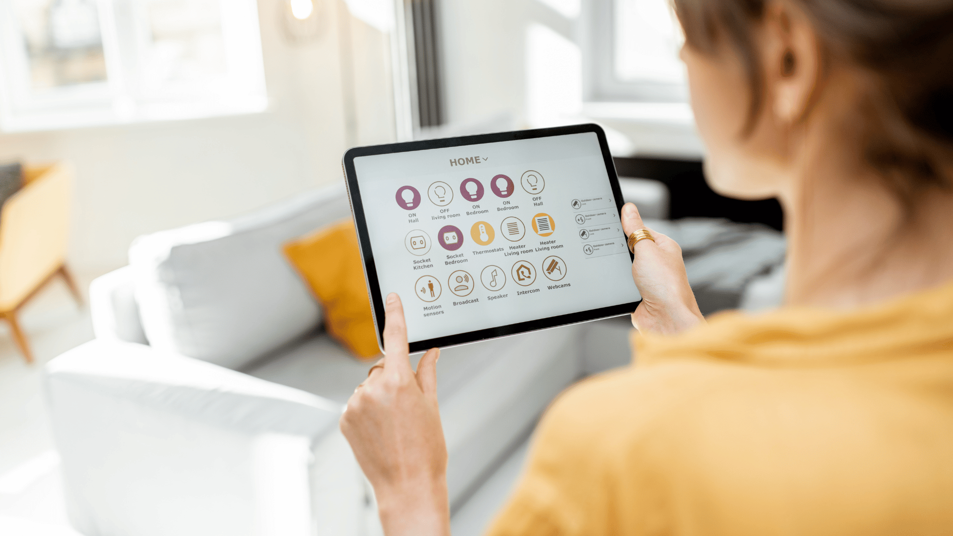 Person using a tablet showing app icons in a bright living room