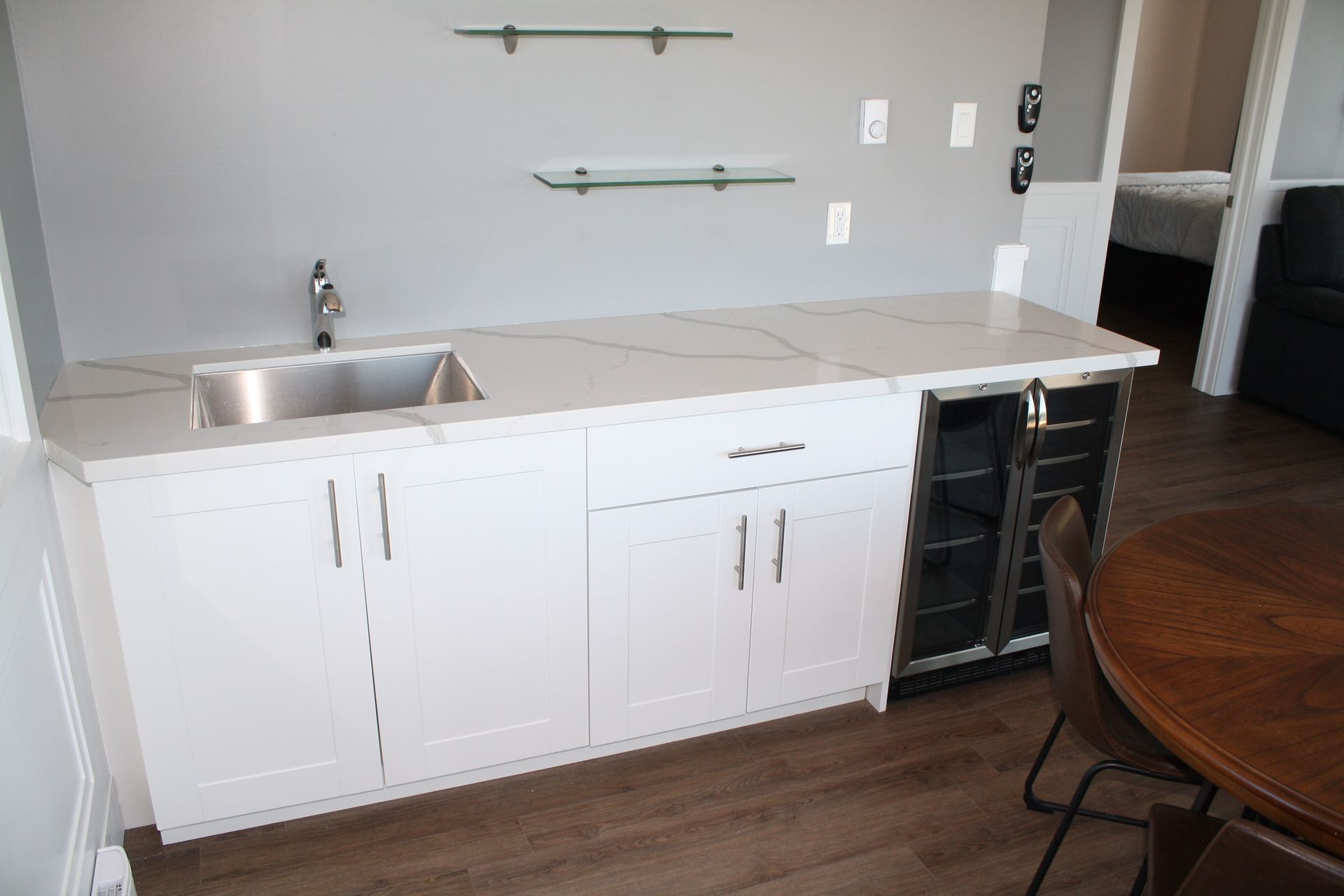 White cabinet bar with a sink, wine fridge, and marble countertop.