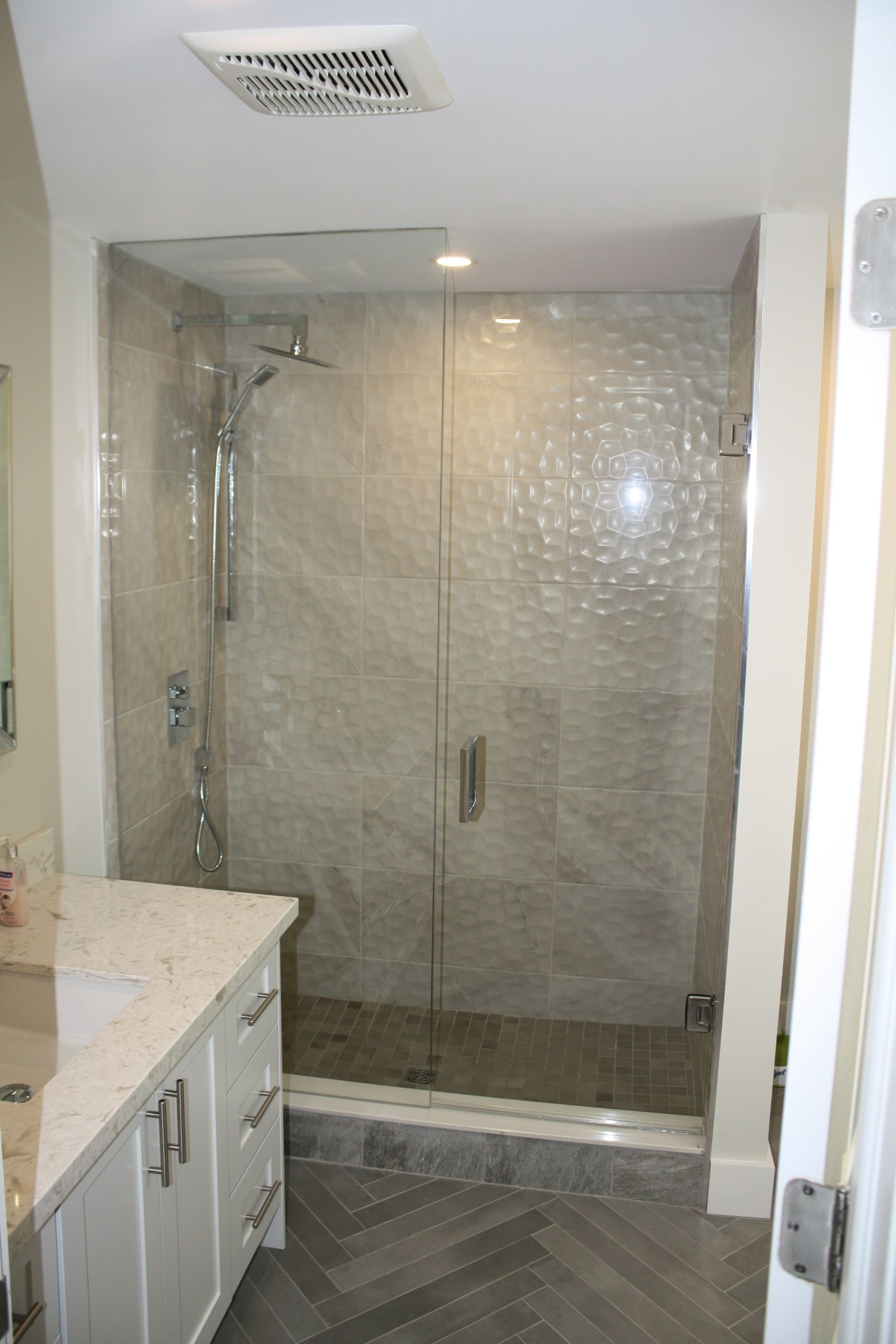 Modern bathroom with a tiled shower, glass doors, and a vanity.