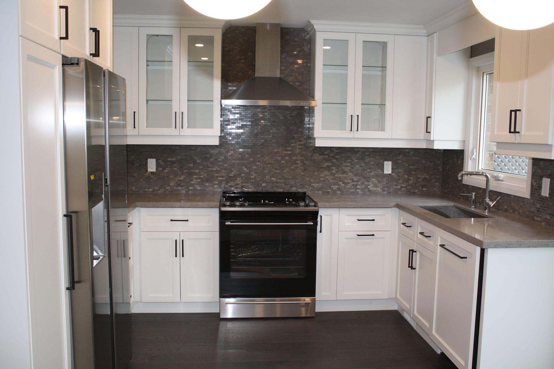 White kitchen with cabinets, stainless steel appliances, and dark backsplash.
