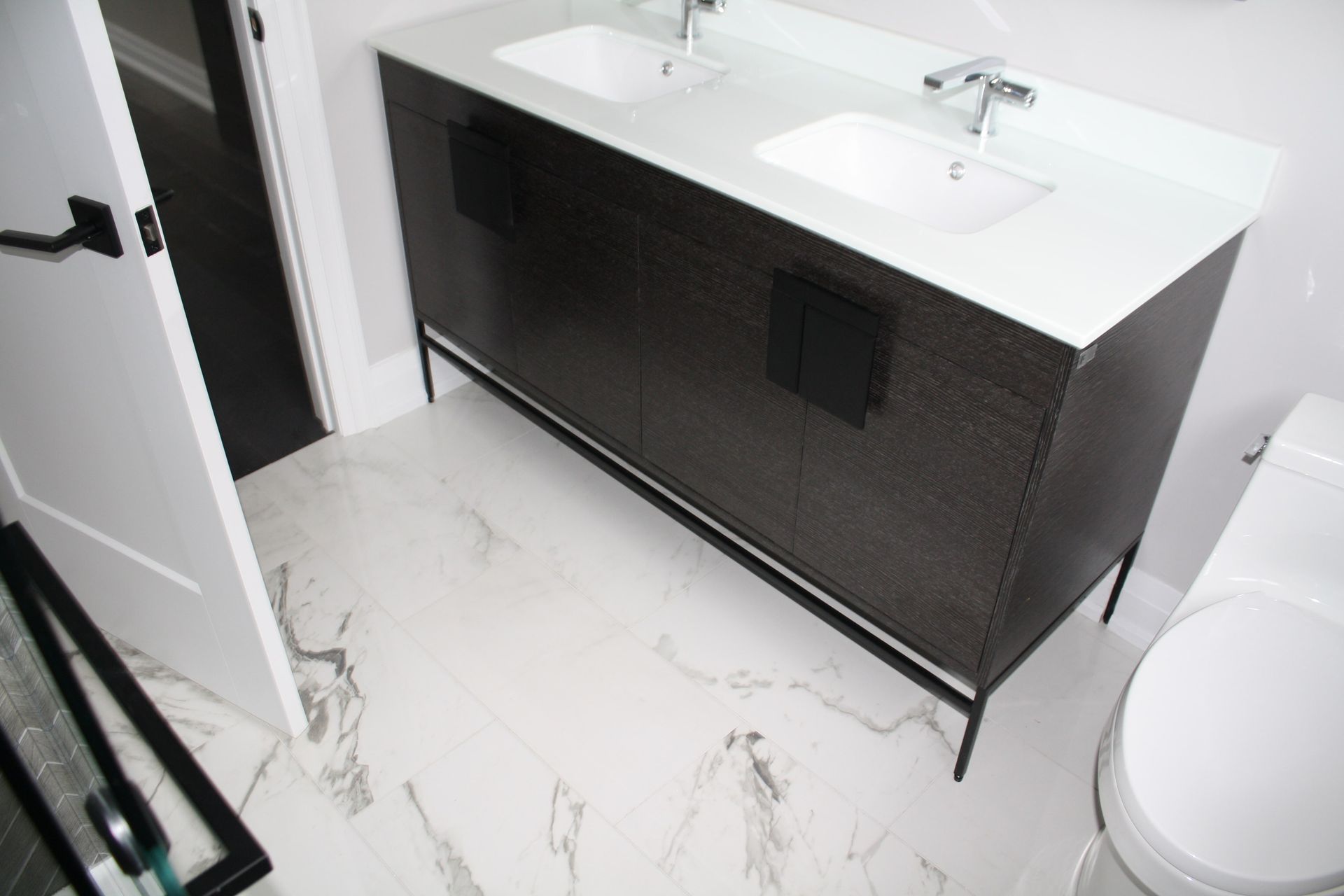 Dark wood double vanity in a modern bathroom with marble-patterned floor.