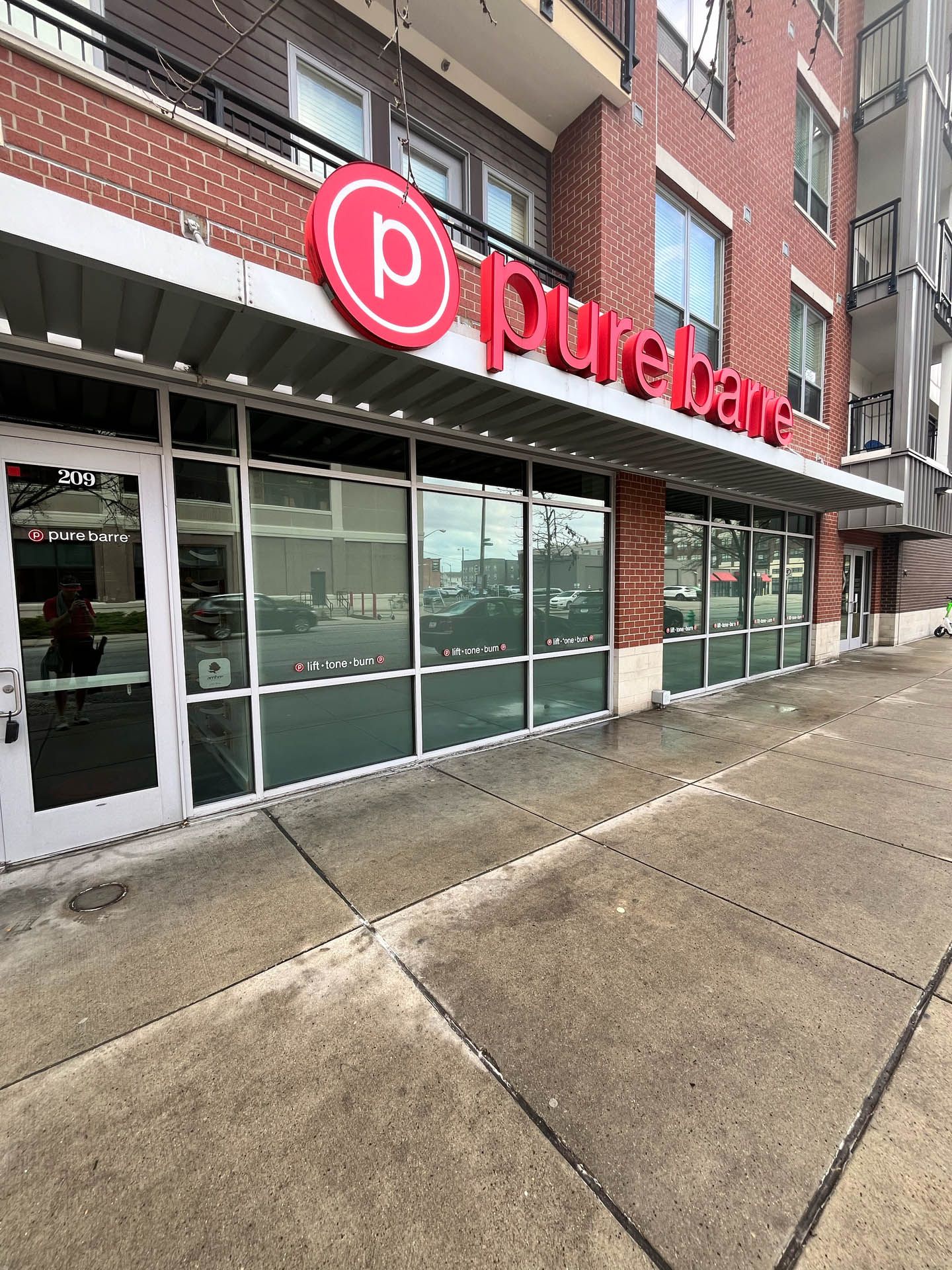 Storefront of Pure Barre with red logo and large glass windows on a wet sidewalk