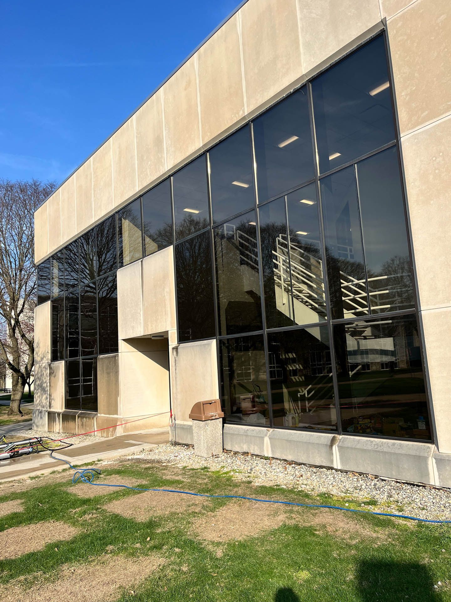 Modern building with large reflective glass windows and a beige facade under a clear blue sky